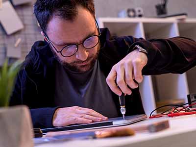 a man is unscrewing the cover off a notebook computer